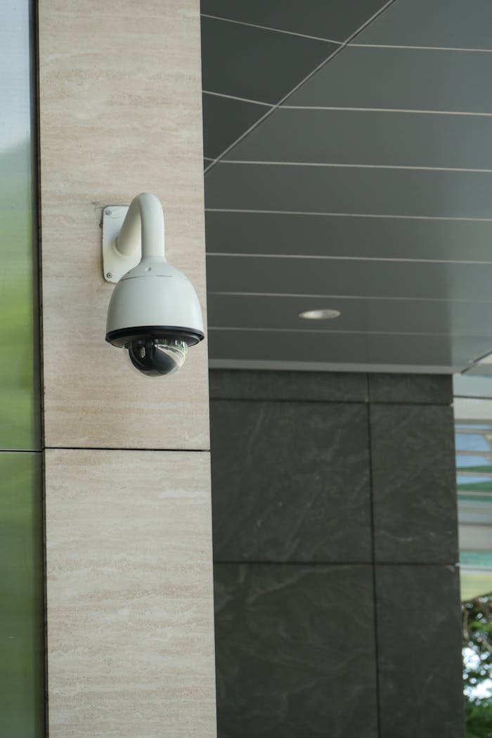 about-us Close-up of a mounted security camera on a modern building's exterior.